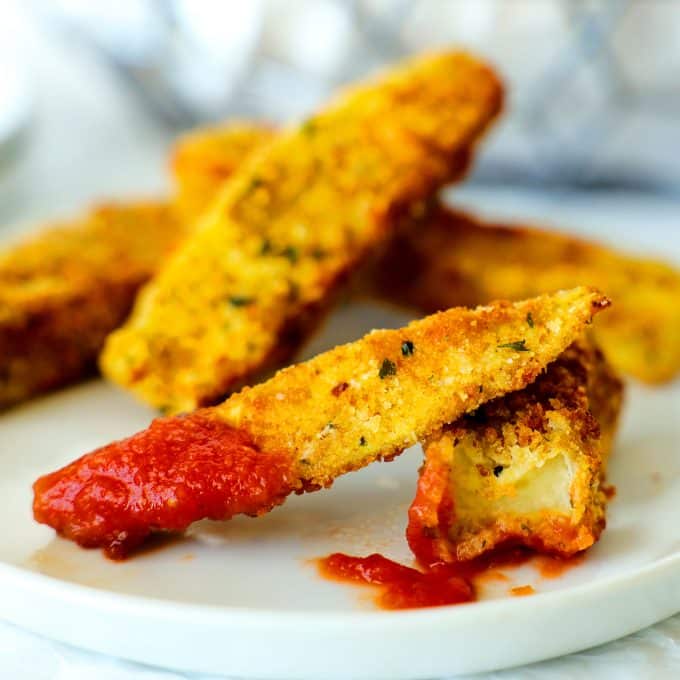 Air fryer eggplant that has been dipped into marinara and a bite taken out of it.