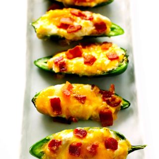 Jalapeno Poppers in a line on a white, rectangle platter.