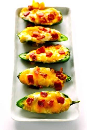 Jalapeno Poppers in a line on a white, rectangle platter.