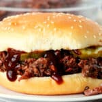 A chopped beef sandwich on a white plate.