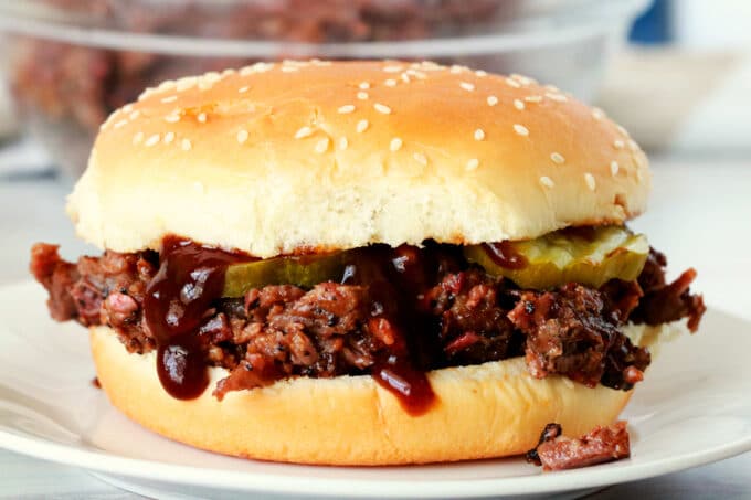 A chopped beef sandwich on a white plate. 