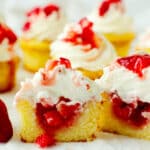 A group of strawberry shortcake cupcake cut in half with strawberries spilling out the center.