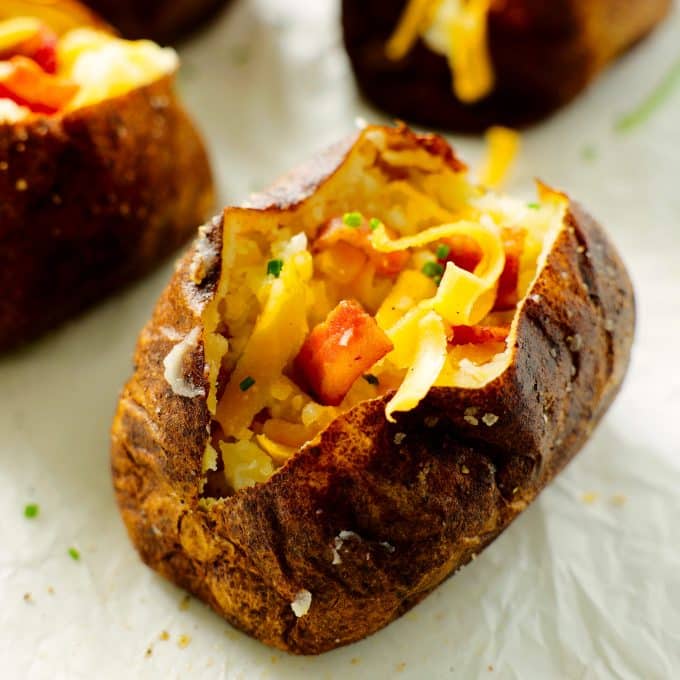 An air fryer baked potato split open with bacon and cheese inside.