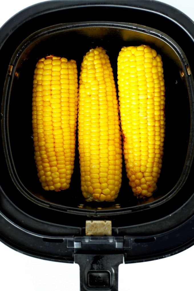 Three cobs of corn in the air fryer basket.