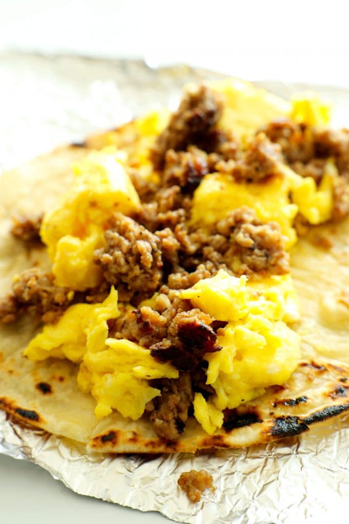 A sausage and egg breakfast taco open-faced on aluminum foil.