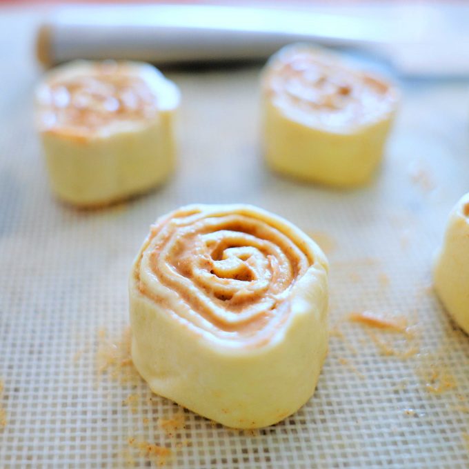 Cinnamon swirls rolled, unbaked on a work surface.