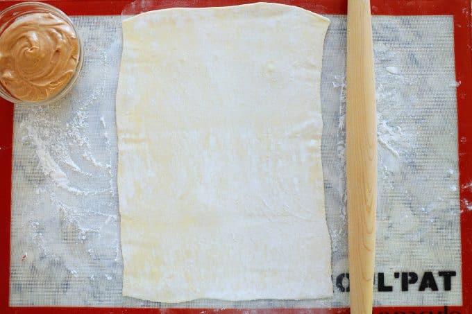 A sheet of puff pastry rolled out on a floured work surface.