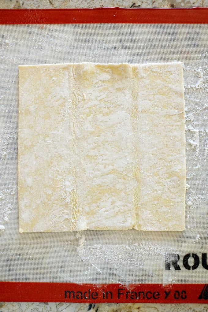 A sheet of puff pastry on a floured work surface.
