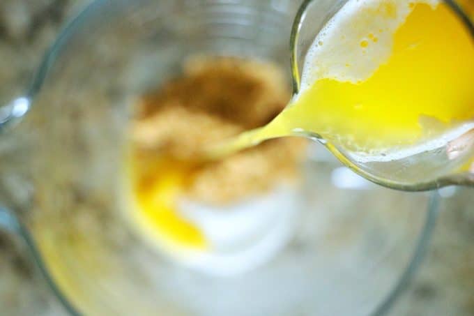Butter being drizzled into a bowl with sugar and water.