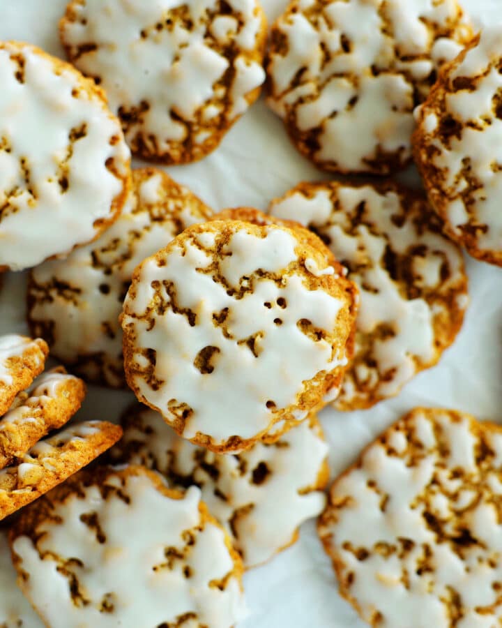 An overhead shot of iced oatmeal cookies on a sheet of parchment paper.