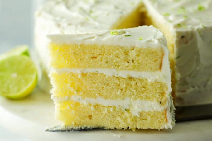 A slice of key lime cake on a cake stand.