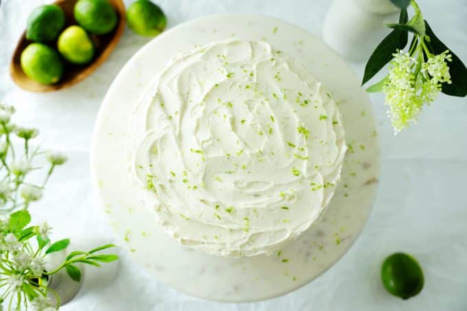 An overhead shot of key lime cake with limes off to the side. 