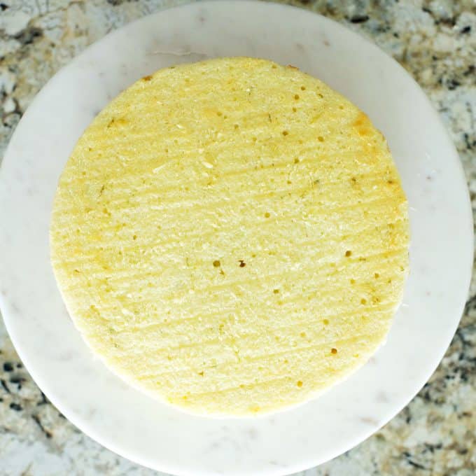 A bare round cake on a cake stand.