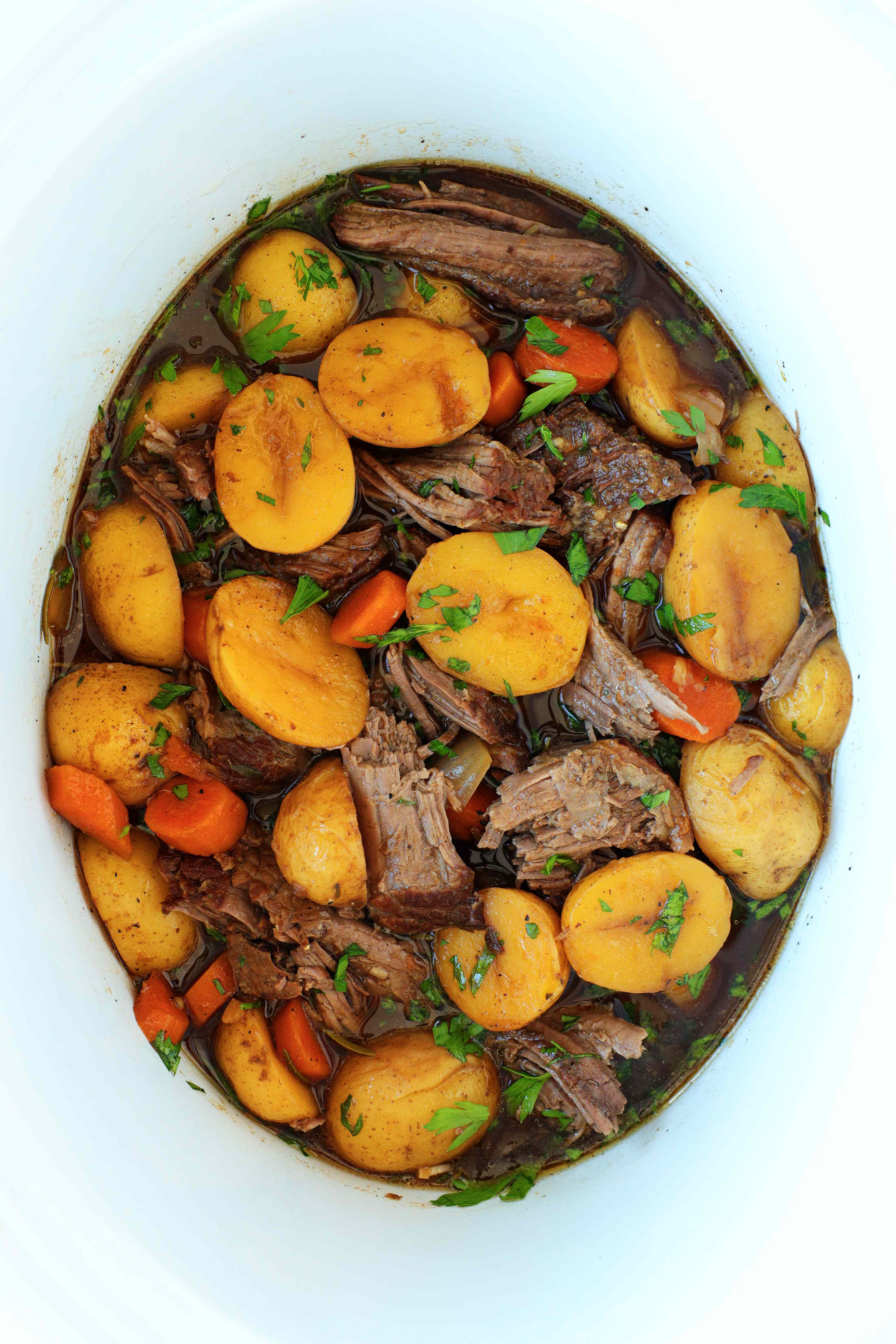rump roast in a slow cooker fully cooked and shredded with potatoes and carrots