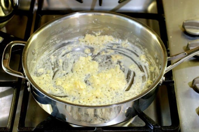 Butter, flour, and fresh chopped garlic in a sauce pan cooking on the stove top.