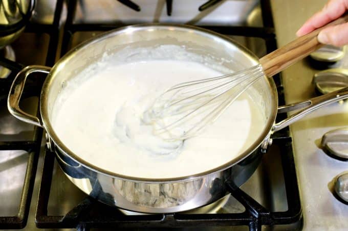 Alfredo sauce being whisked together on the stove top.