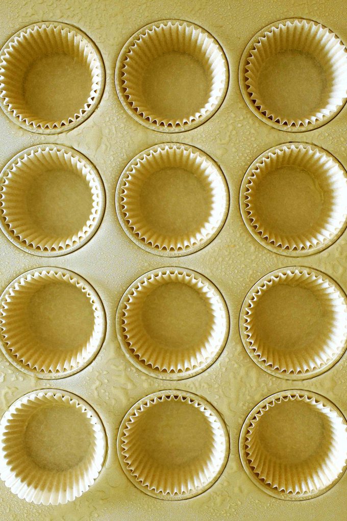 And overhead shot of a muffin pan lined with cupcake liners and spritzed with oil.