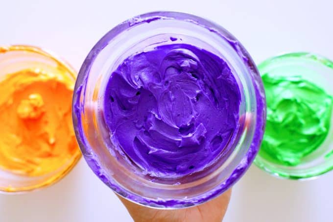 Purple, orange, and green butter cream frosting and clear bowls.
