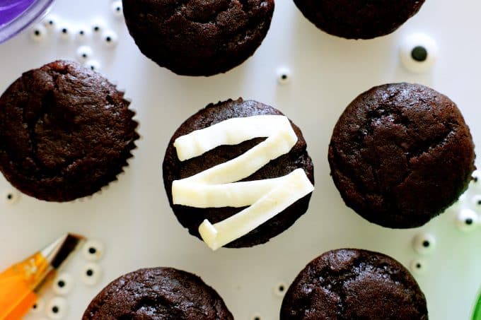 Chocolate cupcakes with one cupcake in the middle with a zigzag of white frosting on it.