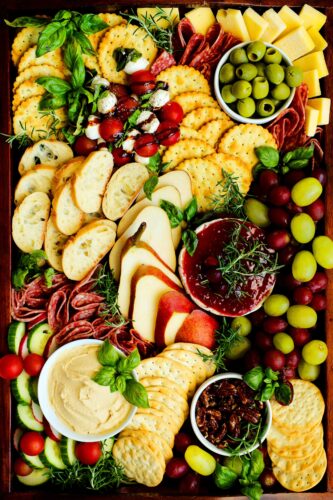 An overhead shot of a Christmas charcuterie board with meats, cheeses, fruits, and more.