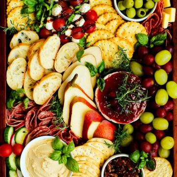 An overhead shot of a Christmas charcuterie board with meats, cheeses, fruits, and more.