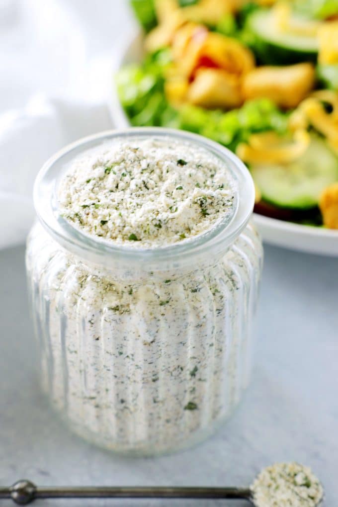 Ranch dressing mix in a bottle with a house salad behind it.