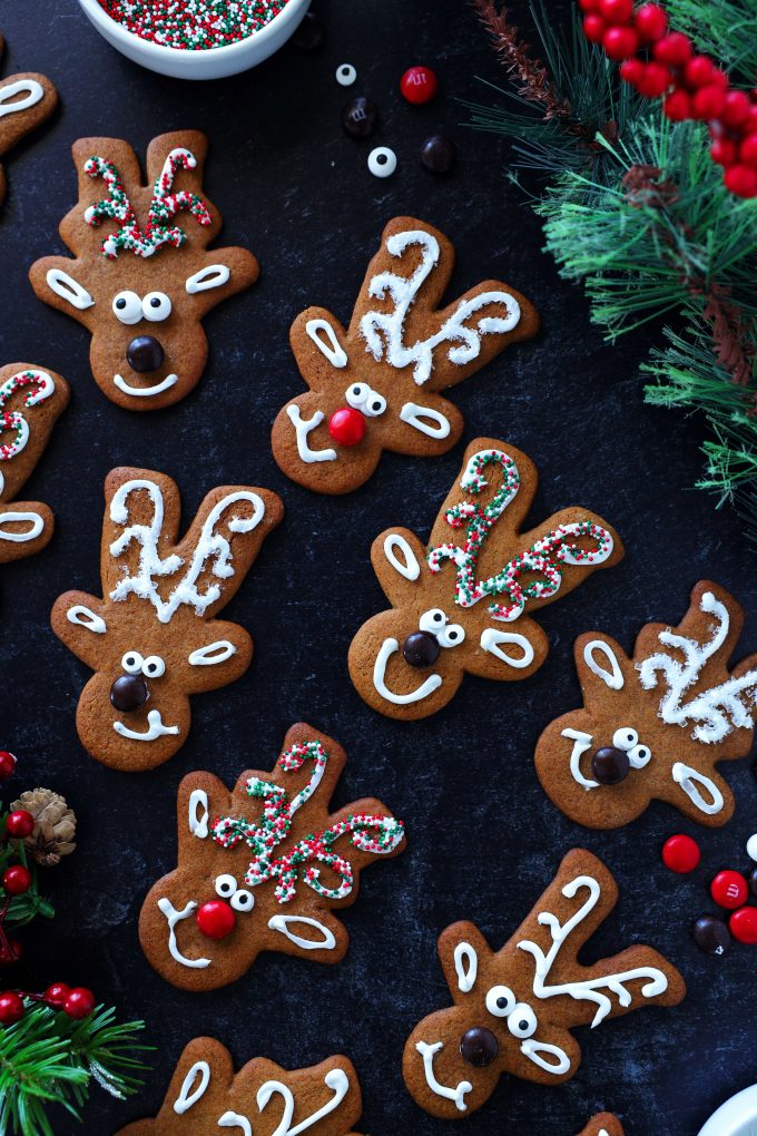 Decorated reindeer cookies staggered on a black surface.