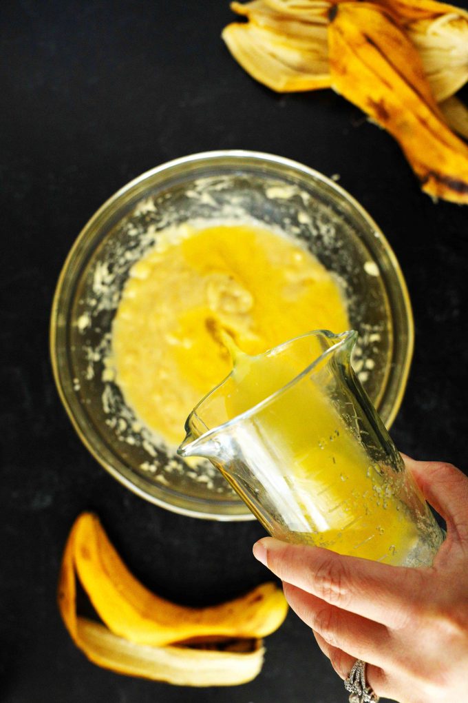 Melted butter being poured over mashed bananas.