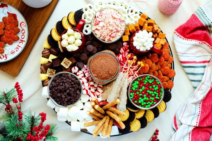 A fully assembled hot chocolate charcuterie board with peppermint candies, cookies, chocolates, and more!