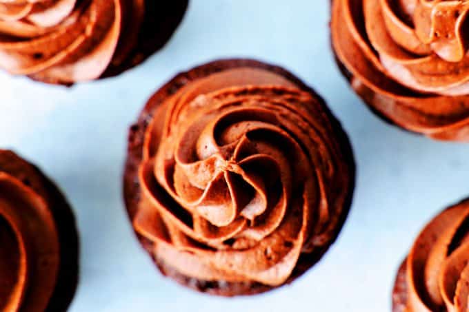 An overhead shot of chocolate cupcakes with chocolate buttercream frosting.