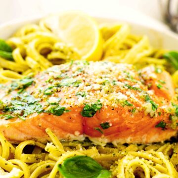 A close up shot of a fillet of salmon on top of pasta.