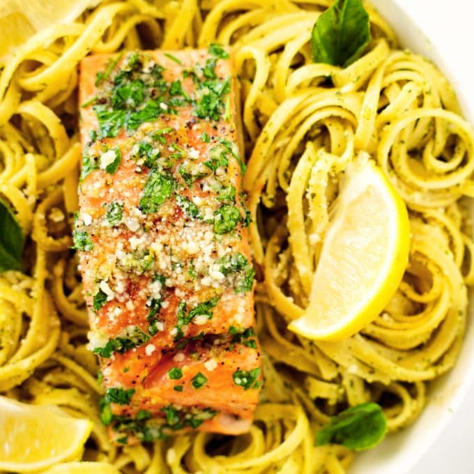An overhead shot of a salmon fillet on top of swirled linguini pasta.