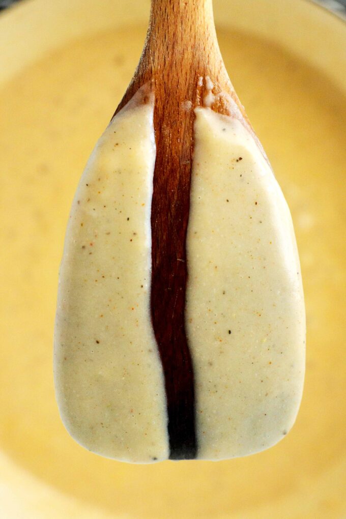 A wooden spoon with gravy on it and a line drawn down the middle.