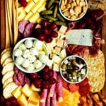 A fully assembled simple charcuterie board with meats, cheeses, fruits, pickled items and crackers.