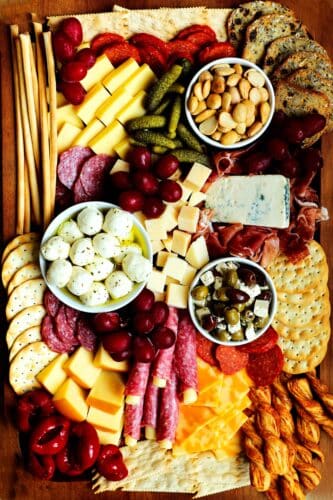 A fully assembled simple charcuterie board with meats, cheeses, fruits, pickled items and crackers.