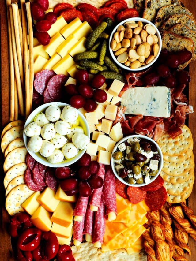A fully assembled simple charcuterie board with meats, cheeses, fruits, pickled items and crackers.