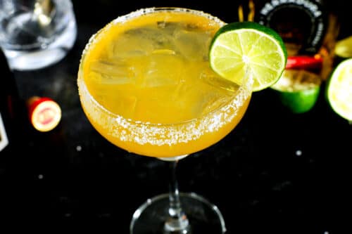 a close up of a margarita with a salt rim and a lime wheel on the side
