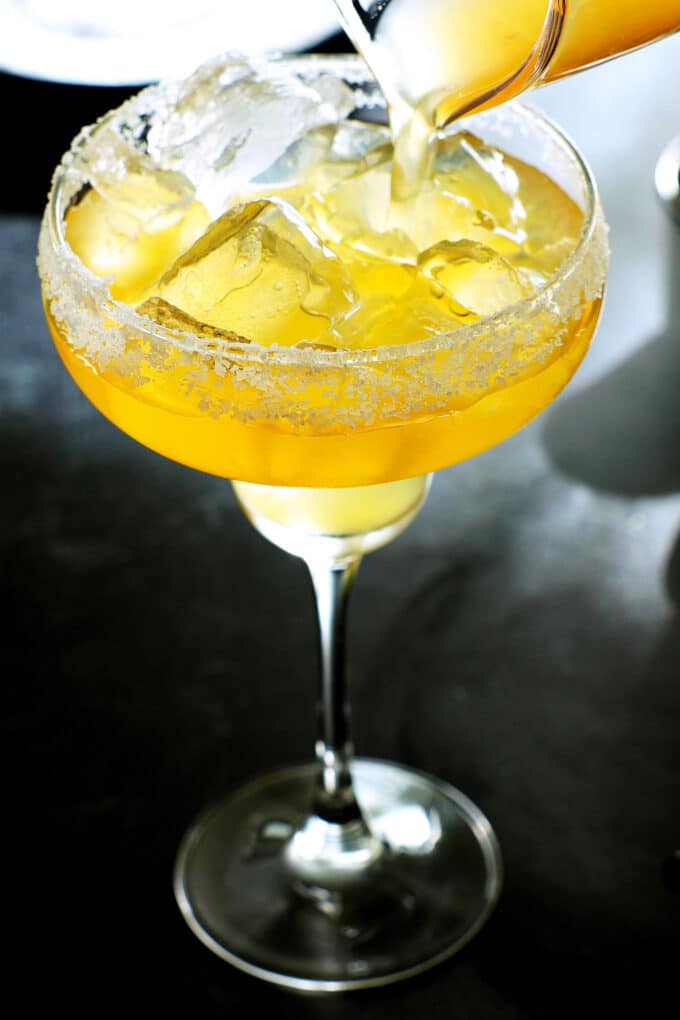 margarita mixture being poured into a glass with a salted rim