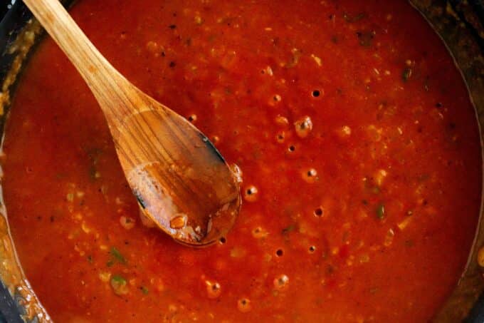 Rojo sauce simmering in a pan with a wooden spoon