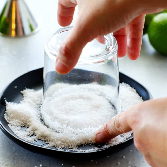 hands swirling an upside down glass on a plate of kosher salt
