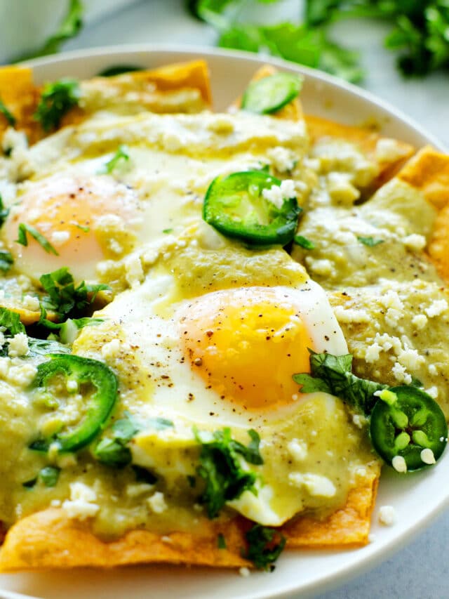 close up chilaquiles verde with fried eggs and jalapeños
