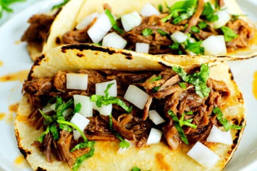 Overhead view of tacos de barbacoa with chopped onions and cilantro on top