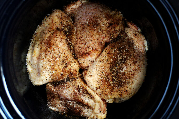 Raw seasoned chicken thighs in a crockpot