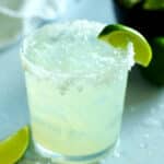 a margarita with a lime wedge on the side and salt rim