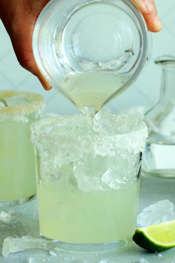margarita mixture being poured into a glass with ice