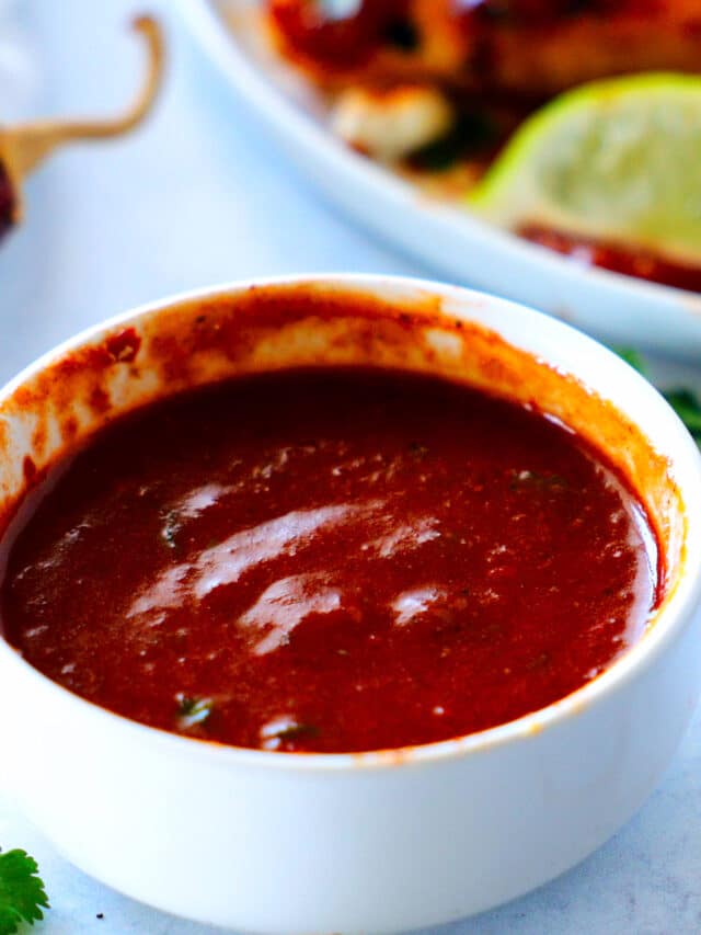 A bowl of Guajillo Sauce in the foreground with a plate of quesadillas in the background