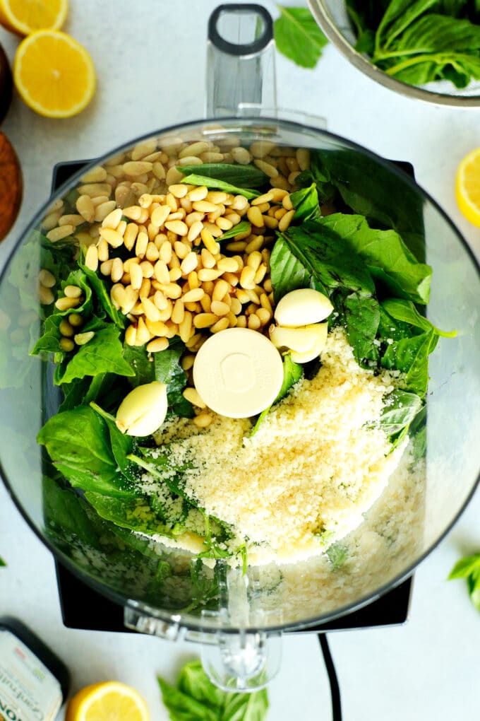 An overhead view of pesto ingredients in a food processor 