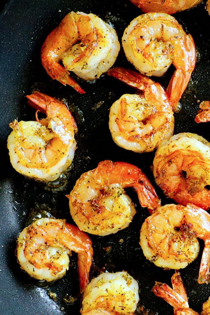 shrimp with tails being seared in a pan
