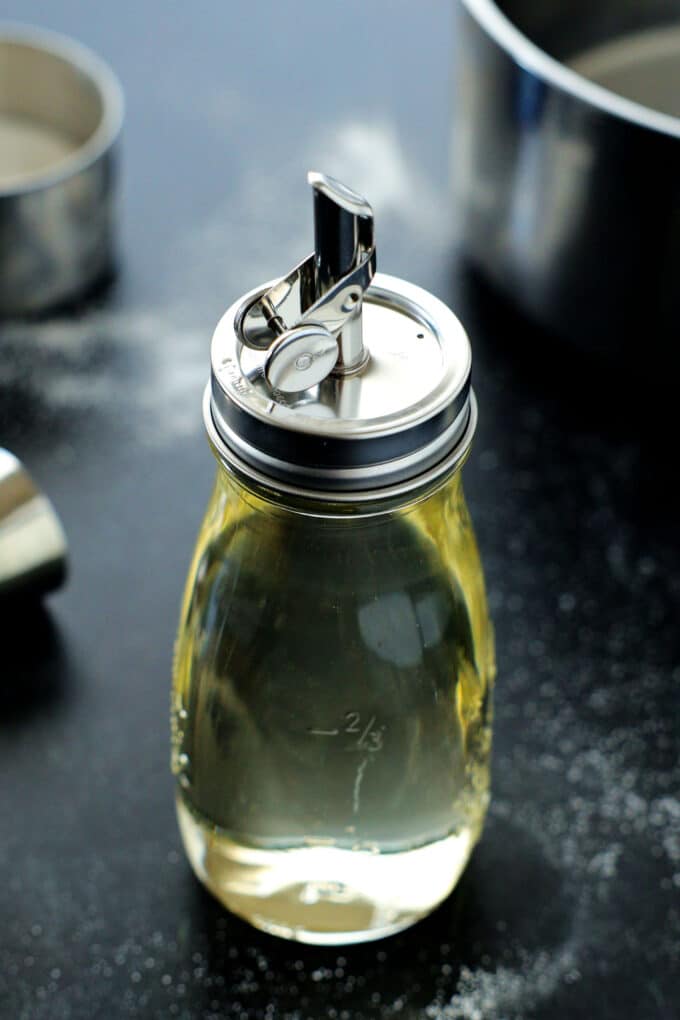 A glass bottle of simple syrup with a pour spout lid