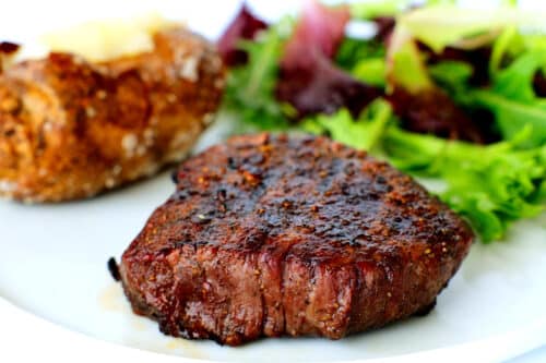 A top sirloin on a plate with potato and salad